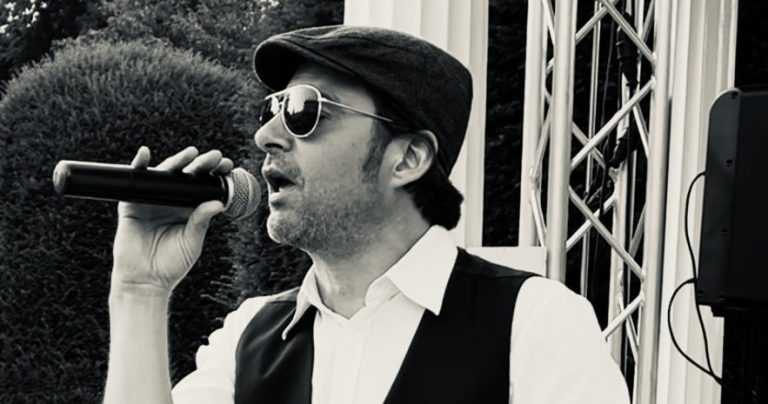 Aufregende Italia Show Mann als italienischer Sänger singt mit Mikrofon, trägt Sonnenbrille und Hut, im Schwarze-Weiß-Stil.