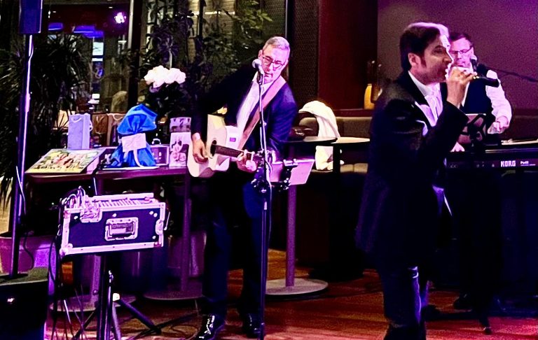 Liveband mit Udo Jürgens Cover Sänger und Instrumenten bei einer Veranstaltung in einem stilvollen Raum.