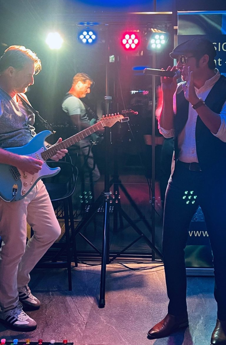 Italienisches Musik Duo Mann mit Sonnenbrille und Mikrofon, singt in einem italienischen Ambiente, daneben ein Gitarrist