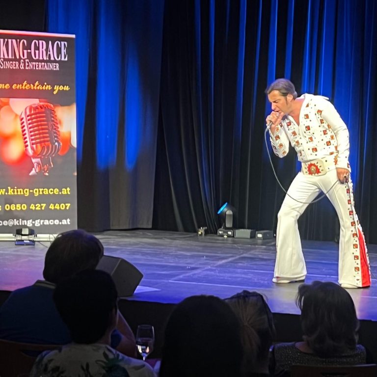 Elvis Imitator Wien Ein Sänger im Elvis-Kostüm tritt auf einer Bühne auf.