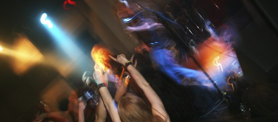 Menschen feiern begeistert bei einem Konzert mit besten Lichteffekten.