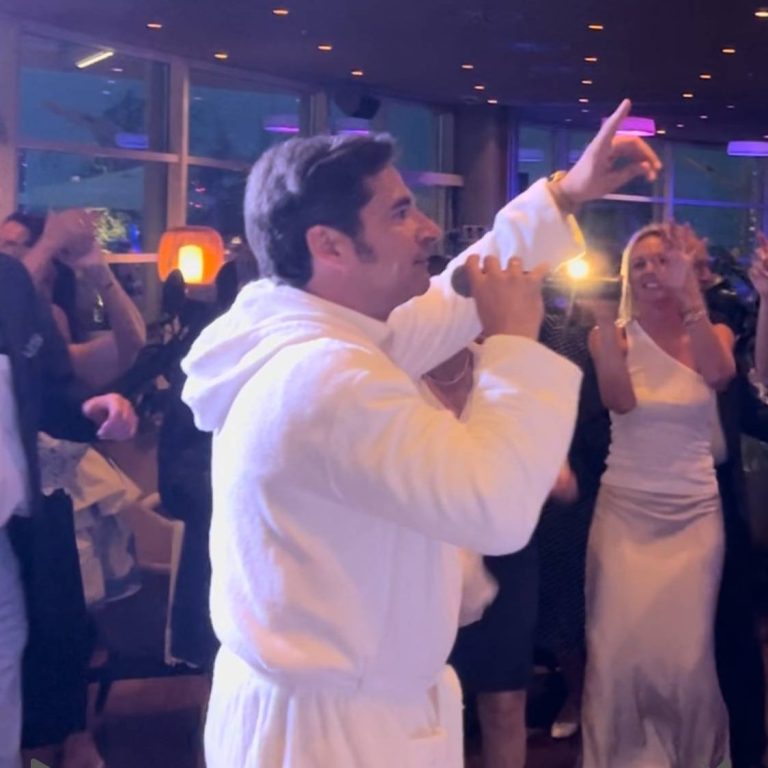 Ein lebhaftes Fest mit Menschen, die gemeinsam mit Udo Jürgens Double Sänger tanzen und feiern, von der Seite strahlendes Bühnenlicht