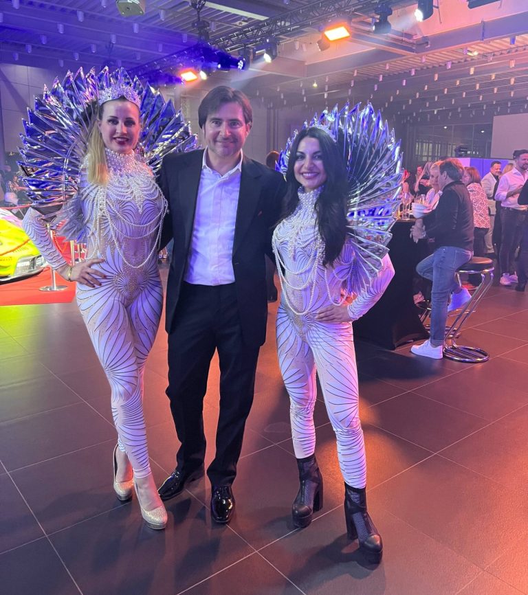 Drei Personen mit glitzernden Kostümen auf einer festlichen Veranstaltung.