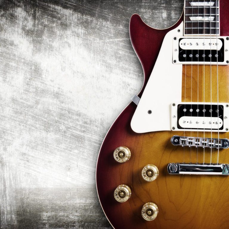 E-Gitarre mit rot-orangefarbenem Finish und silbernen Beschlägen auf grauem Hintergrund.